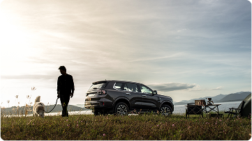 A person walking their dog with a Ford SUV in the background.